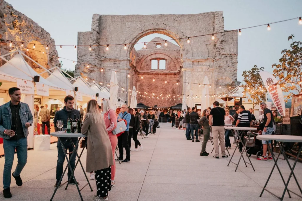 Posjetitelji festivala uz koktel stolove i pagode pokraj ruševina crkve